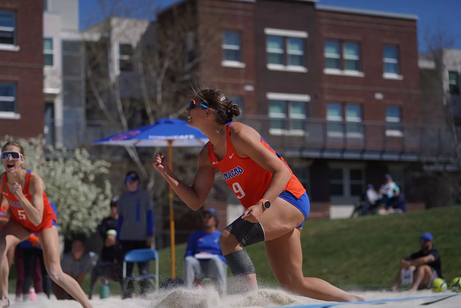 Boise State beach volleyball player rising to serve on the sand