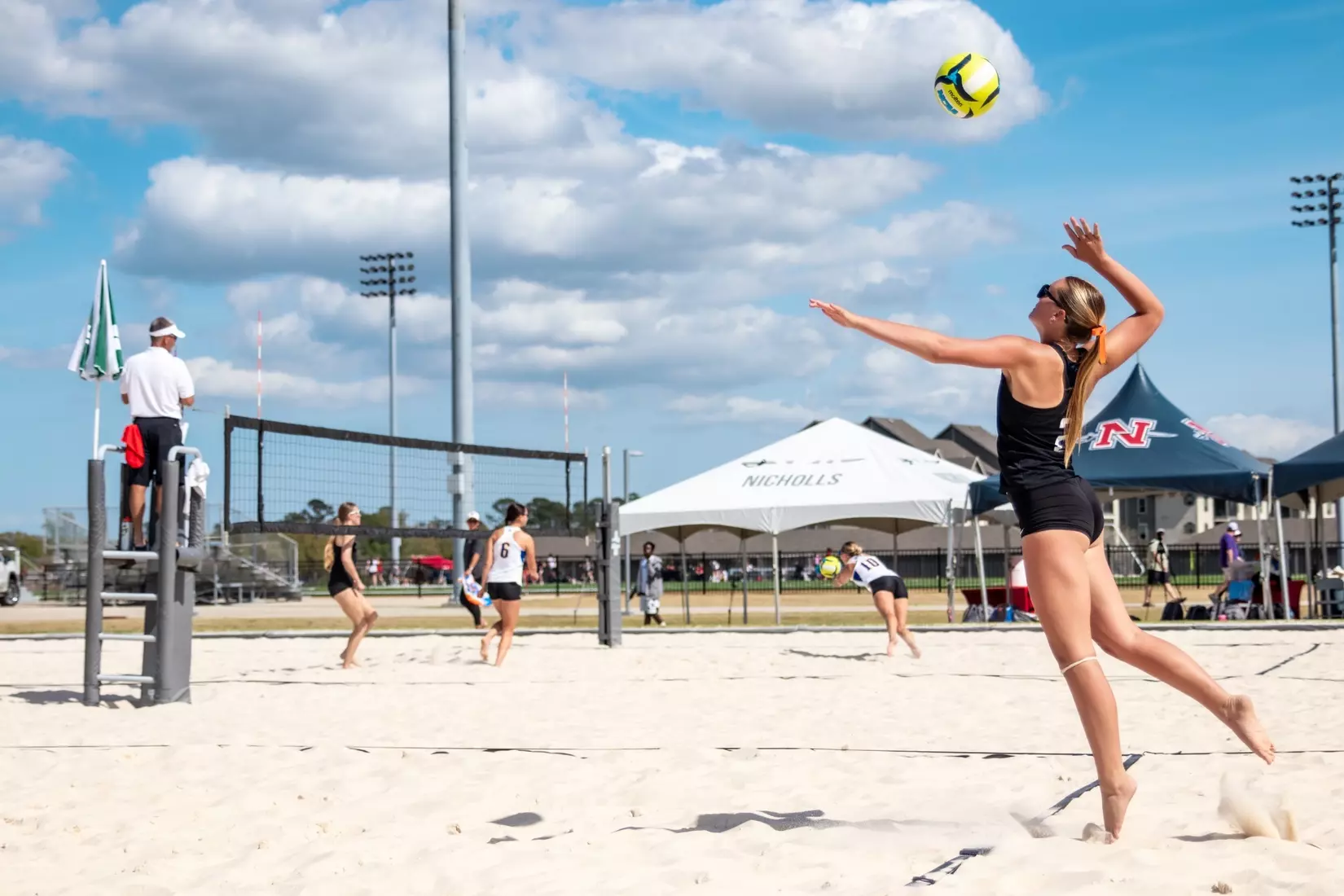 Beach volleyball athletes working through a rally in soft sand