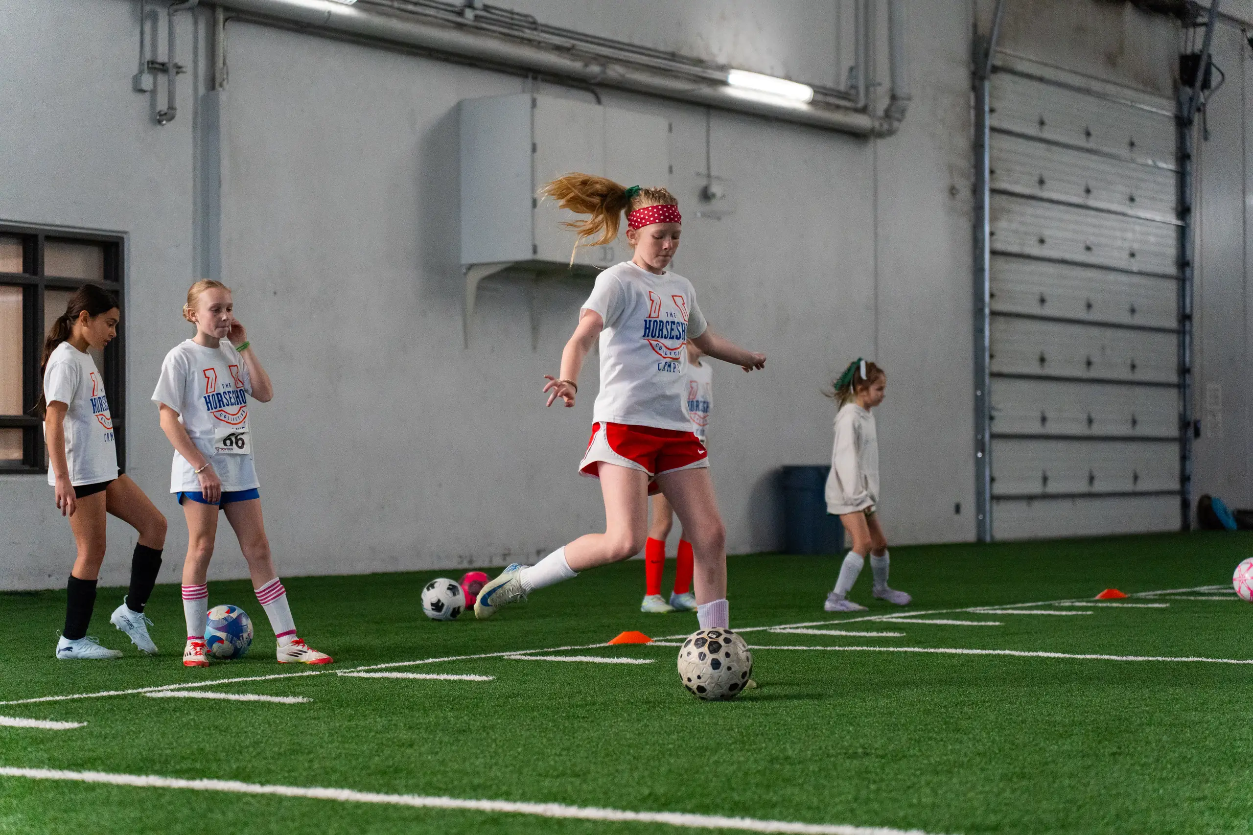 Camper striking a ball on the indoor turf at a past Horseshoe soccer camp