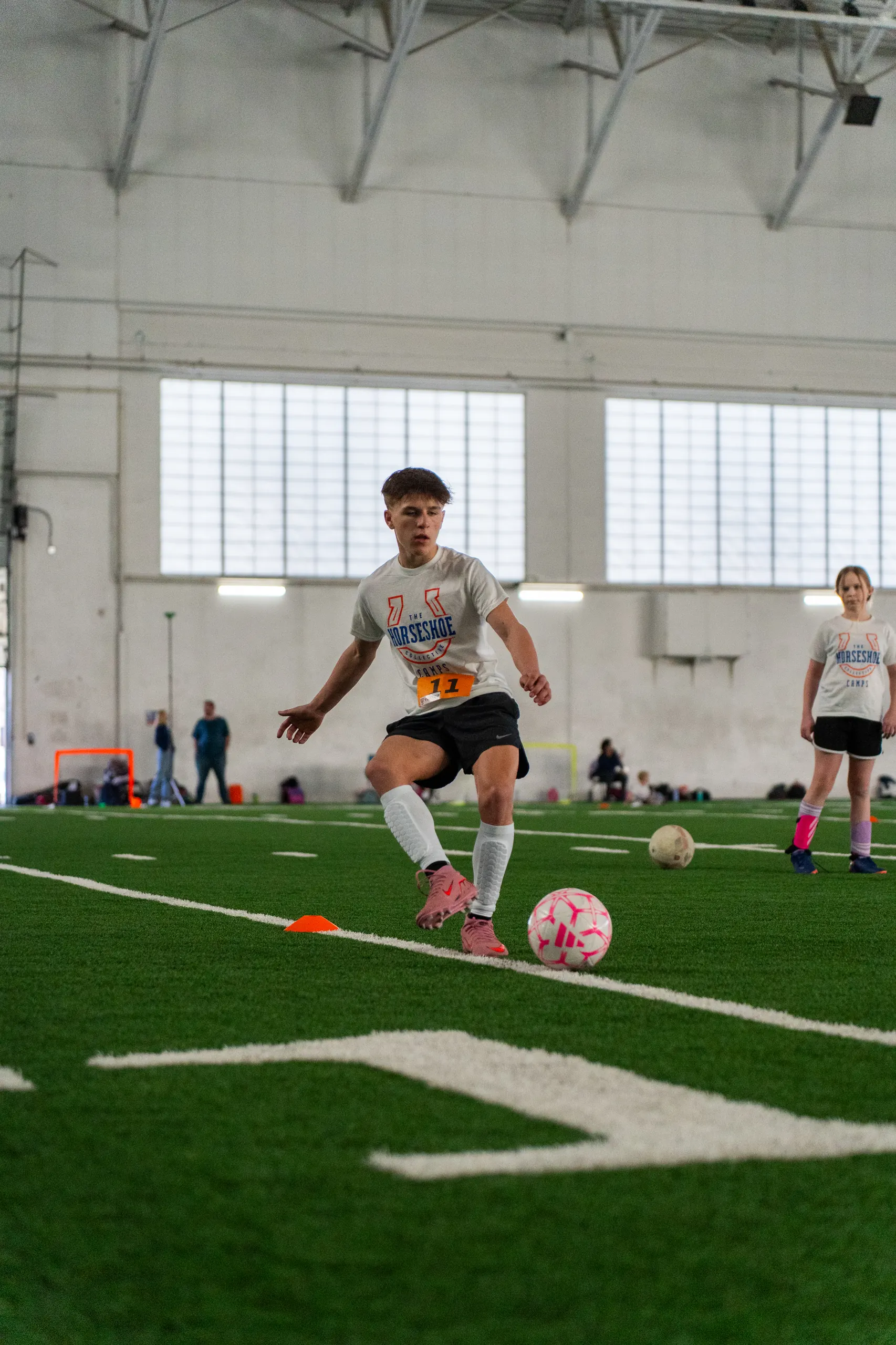 Camper in a Horseshoe Collective camp shirt running onto a ball during drills