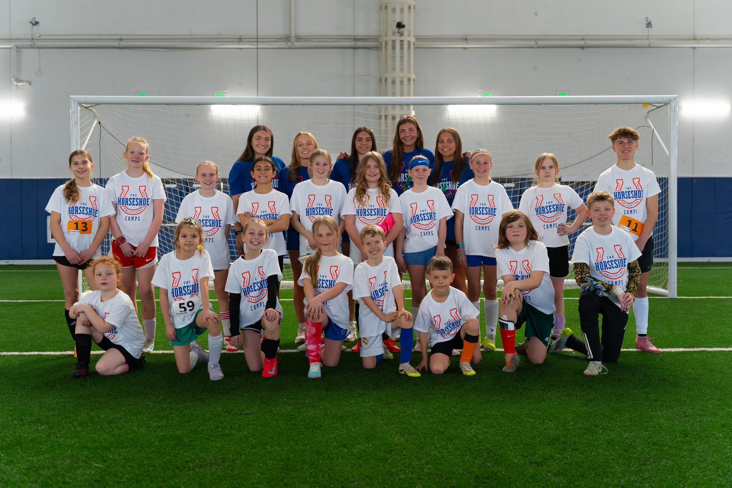 Campers and Boise State Women's Soccer players together in front of the goal at a past Horseshoe soccer camp
