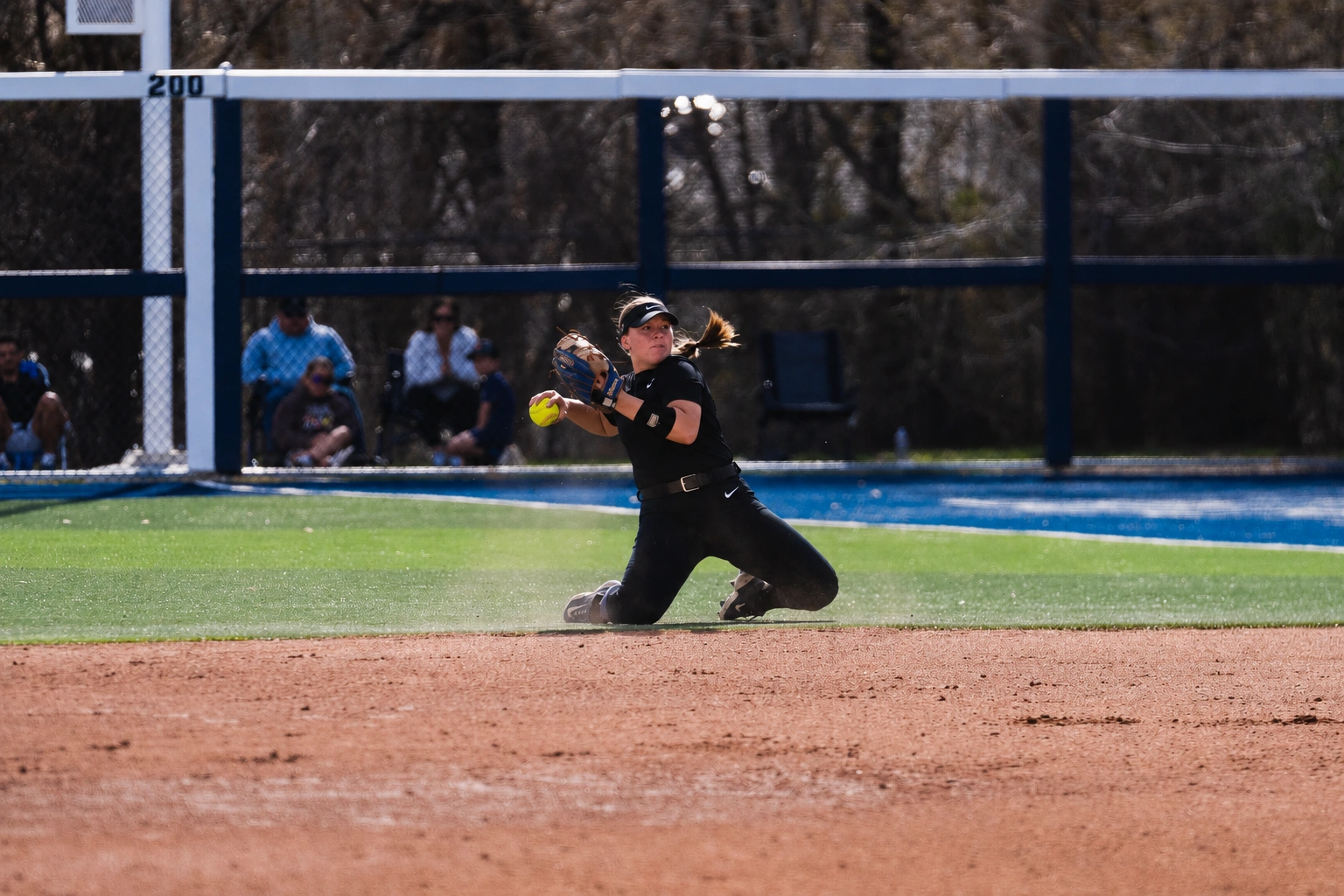 Boise State Softball infielder sliding to field a ground ball and throw